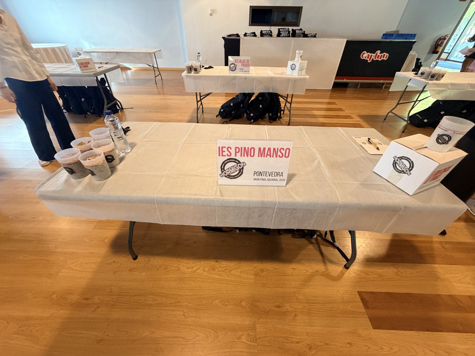 Detalle de la mesa de trabajo del IES Pino Manso (Pontevedra) lista con los vasos de áridos, agua y caja de molde en El Gran Concurso del Hormigón 2026