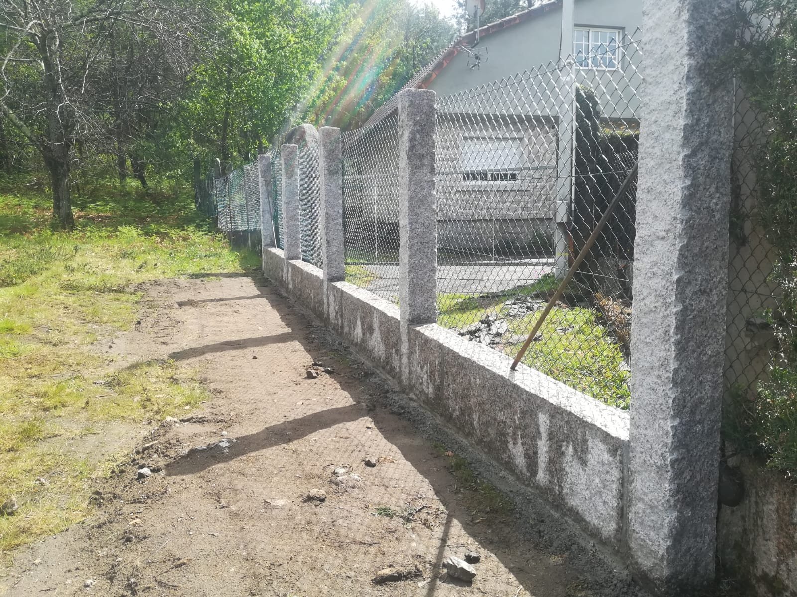 Muro de cierre perimetral con chantos de granito, zócalo de hormigón y malla metálica en suelo rústico en Gondomar