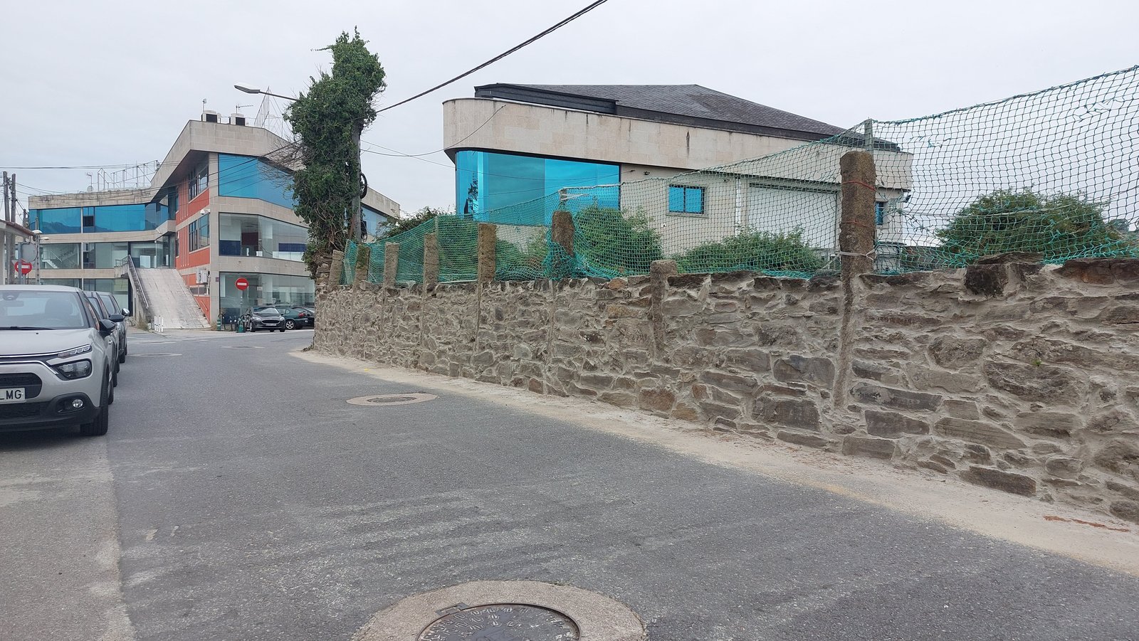 Muro tradicional de piedra reparado y encintado con mortero en vial urbano de Vigo