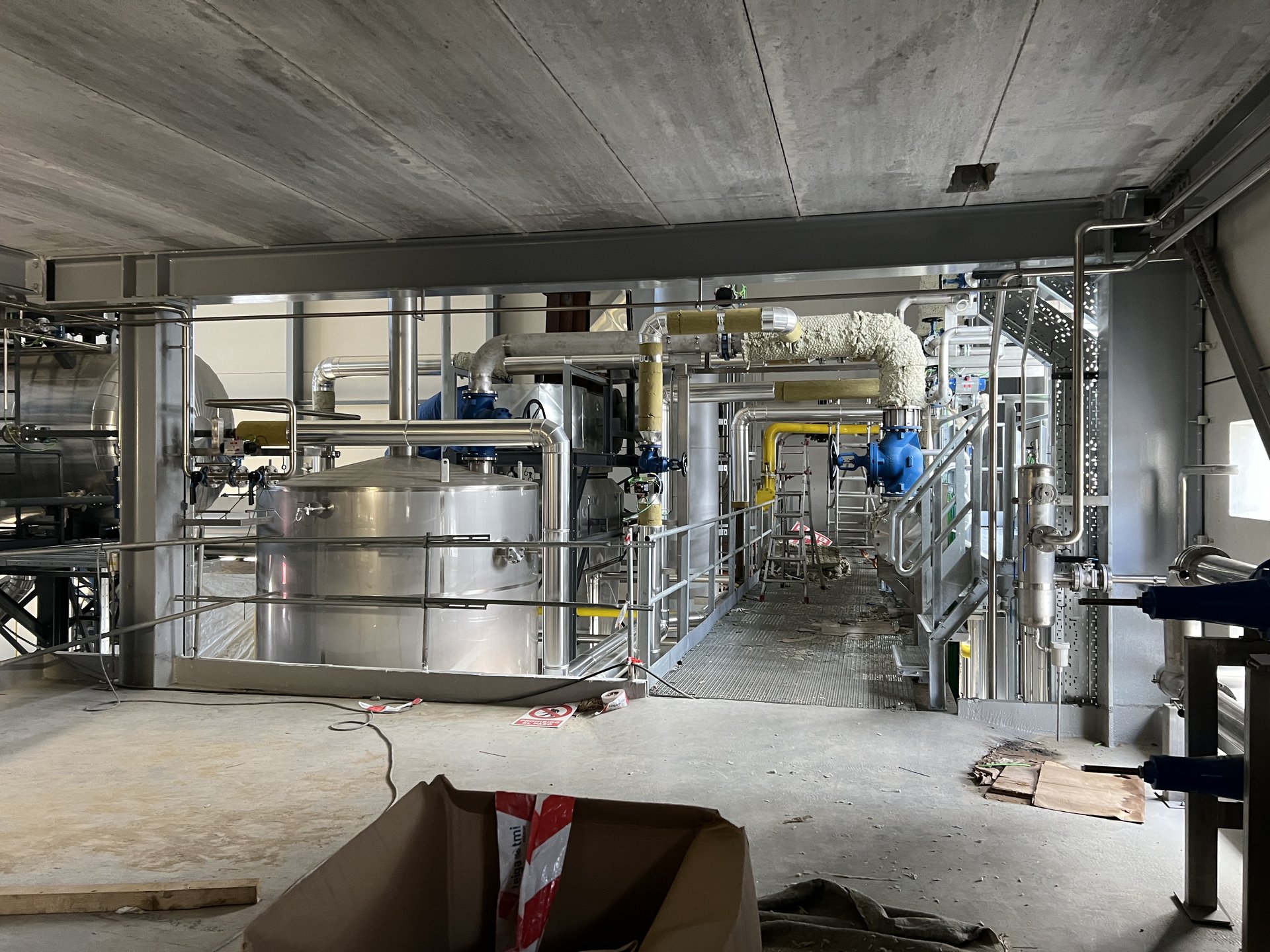 Pasarela técnica de servicio con colectores, valvulería y tuberías calorifugadas en Estrella Galicia