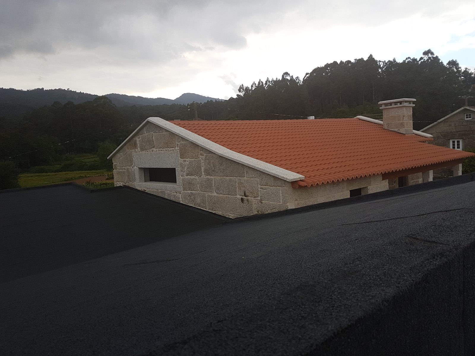 Vista exterior de la cubierta rehabilitada y el nuevo volumen anexo de habitaciones en vivienda unifamiliar en Tui