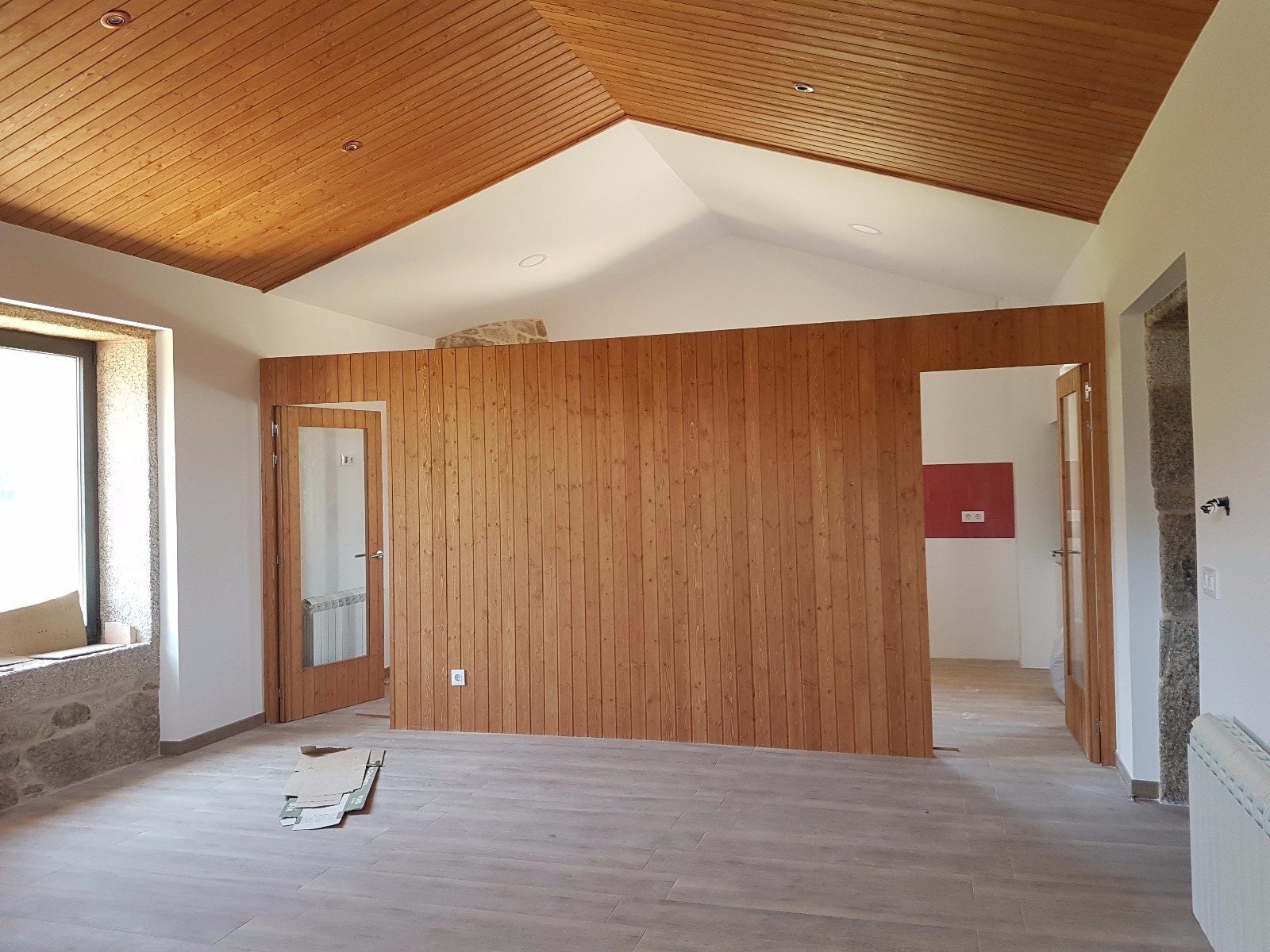 Tabiquería revestida en madera natural bajo cubierta quebrada en forma de Y en vivienda unifamiliar en Tui