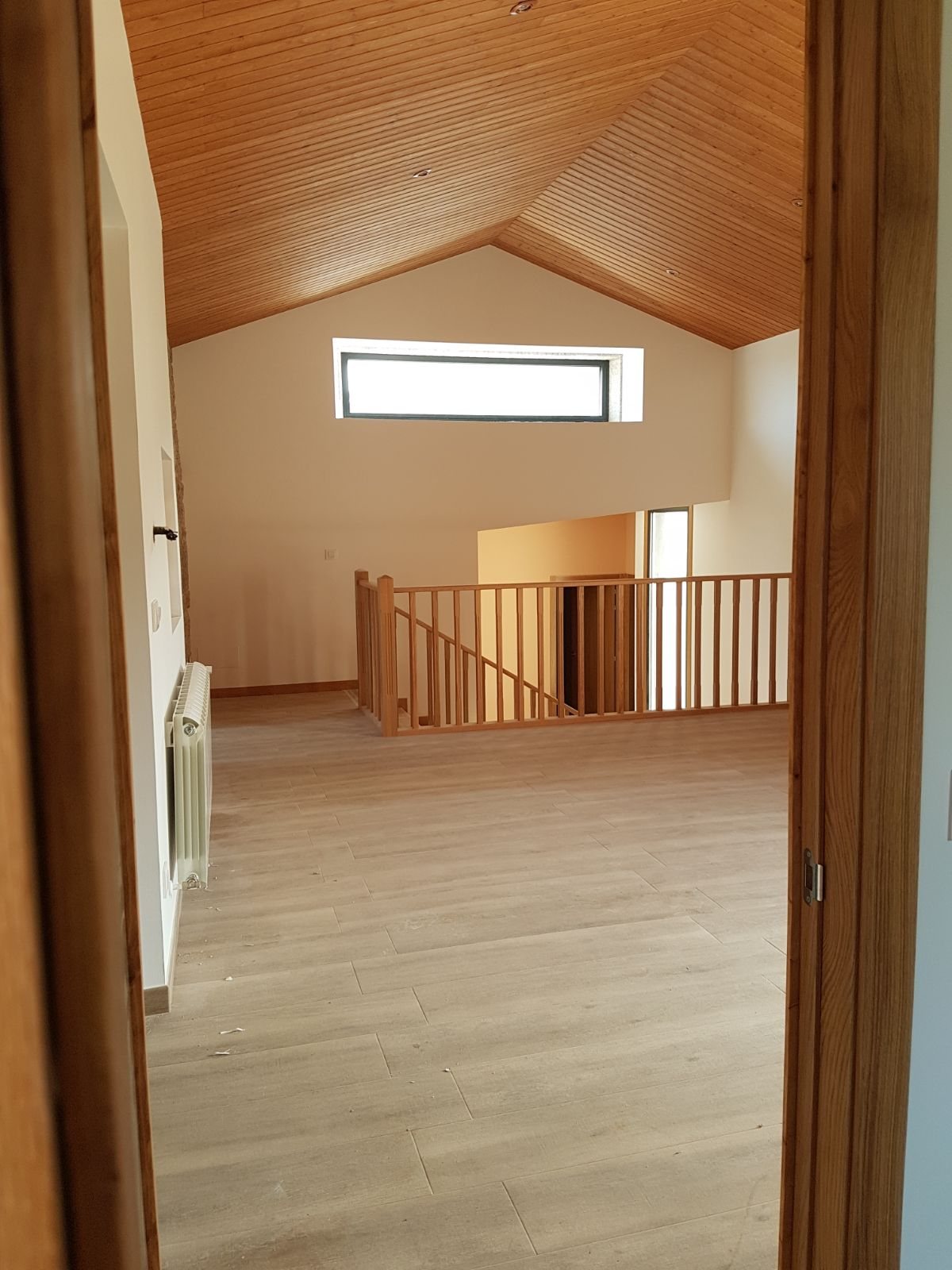 Perspectiva desde las habitaciones hacia la entreplanta y escalera de madera en casa rehabilitada en Tui