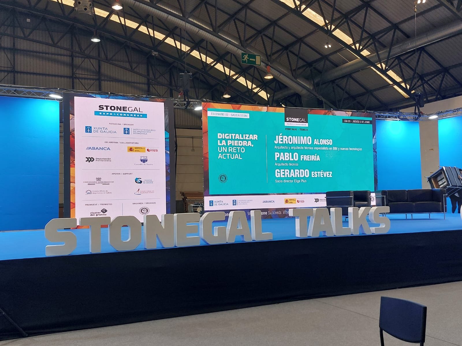 Vista general del escenario Stonegal Talks en IFEVI Vigo con la pantalla Digitalizar la piedra, un reto actual y los ponentes Jerónimo Alonso, Pablo Freiría y Gerardo Estévez