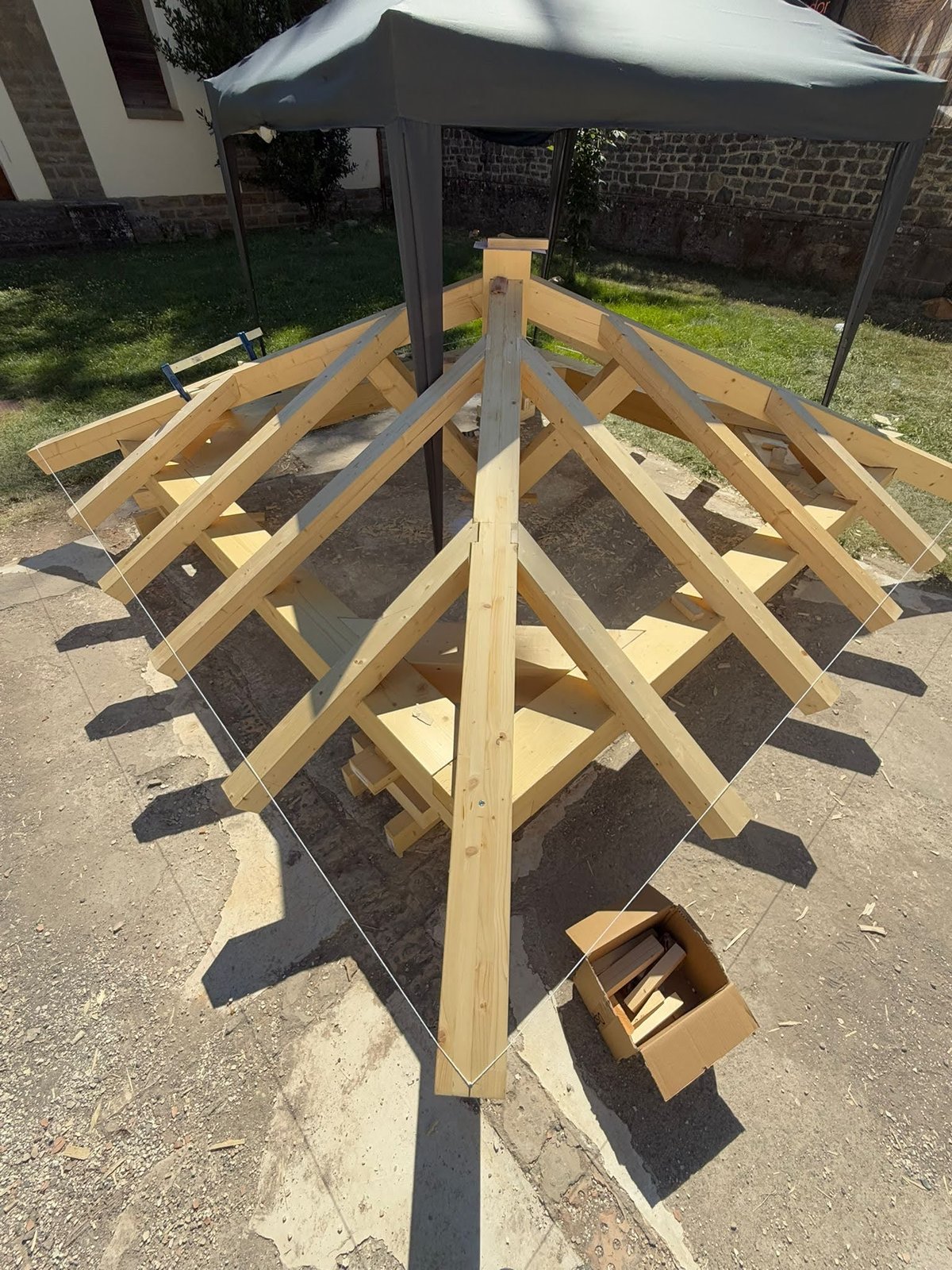 Estructura piramidal de cubierta de madera a cuatro aguas totalmente ensamblada en el patio del obrador de Jaca