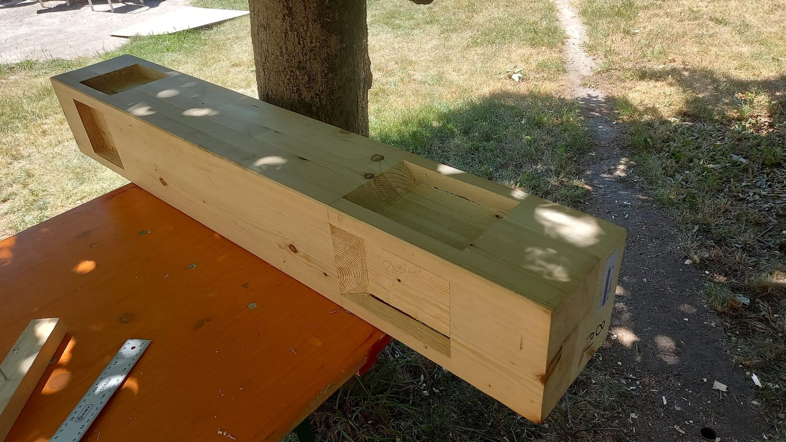 Viga de madera sobre caballetes mostrando múltiples cajas y rebajes tallados con formón