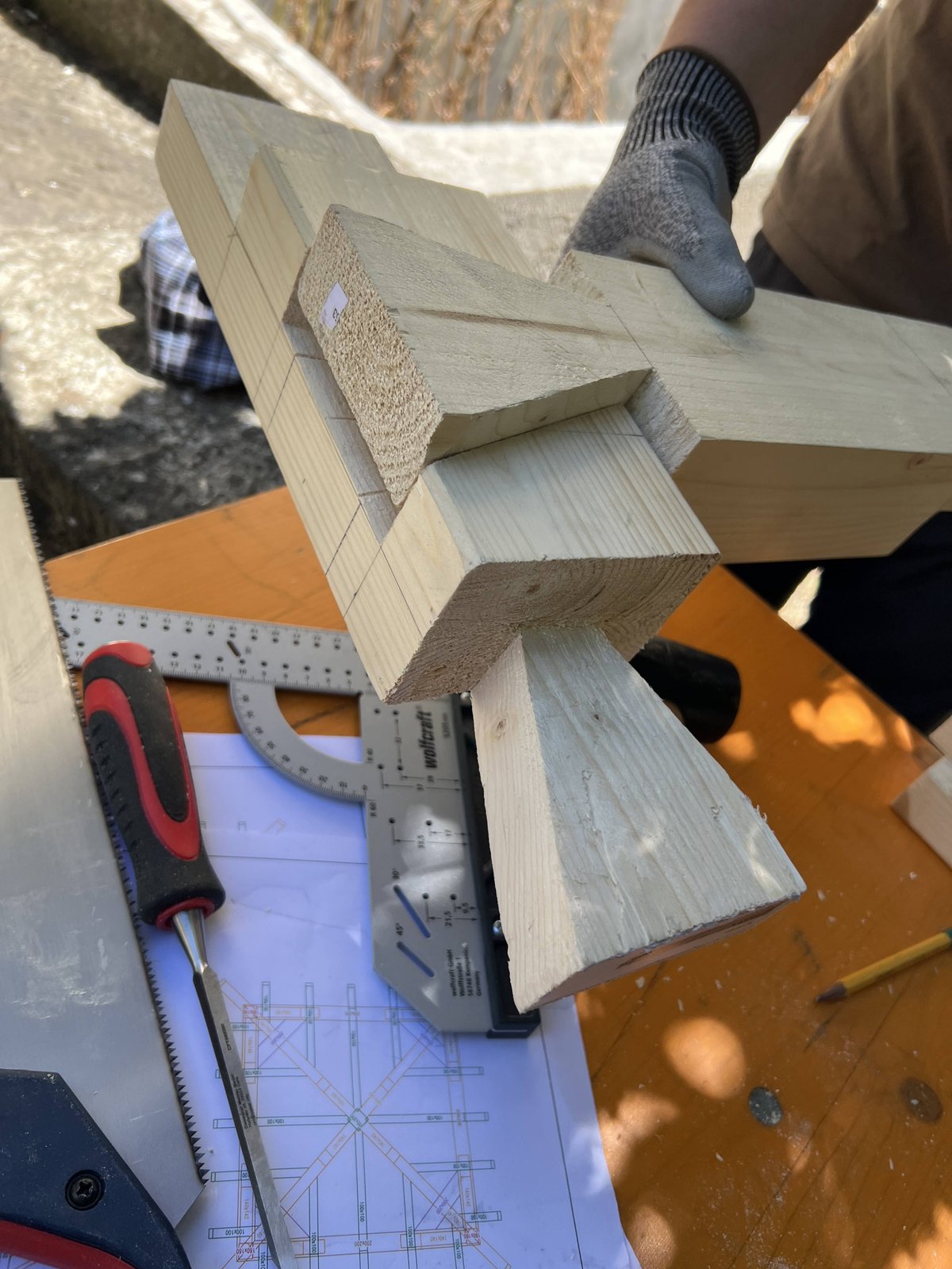 Primer plano de una unión de madera en cola de milano recién labrada sobre los planos de carpintería de armar y falsa escuadra