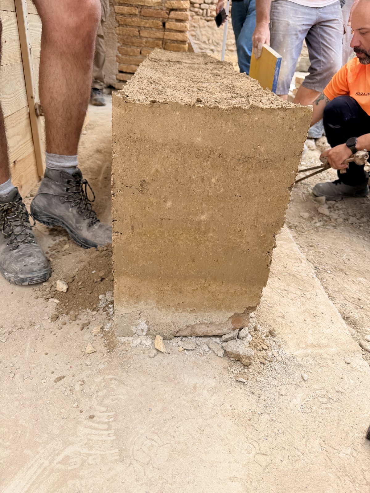 Vista superior de un bloque de tapial monolítico recién desencofrado junto a las herramientas de madera empleadas en su compactación
