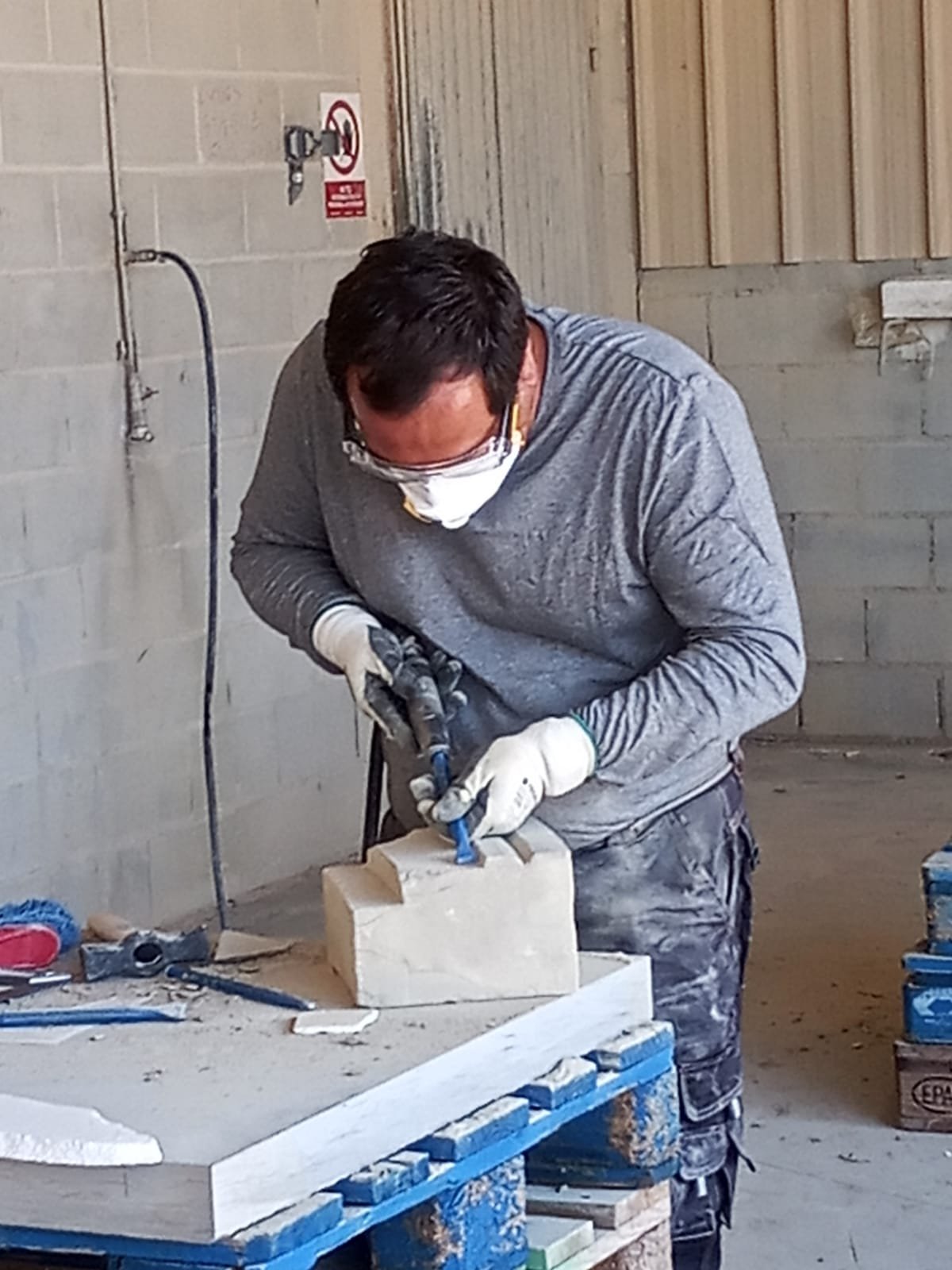Pablo Freiría Lorenzo tallando las molduras de un bloque de piedra arenisca en el banco de cantero en Uncastillo